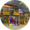 Round image of yellow, indoor playground with yellow, blue, and red slides on the bottom in the center and a tire centered above them
